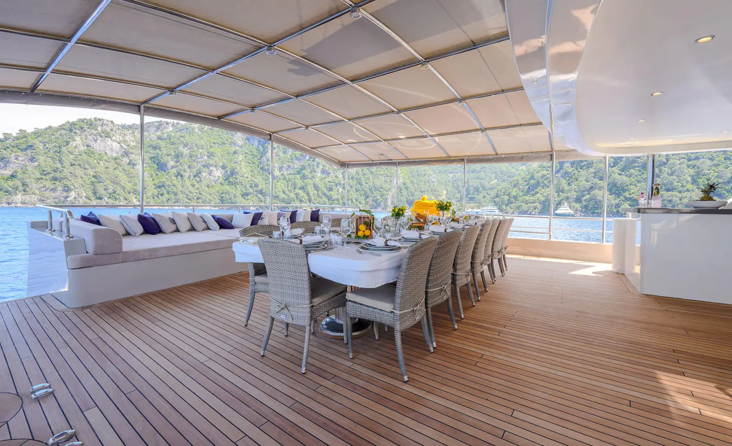 Aft deck lounge area on a yacht with beige seating under a shaded canopy