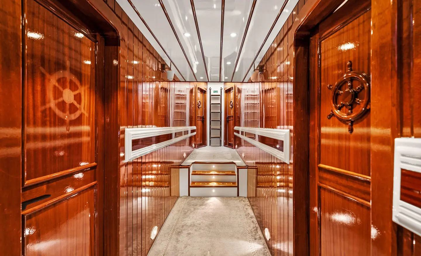 Interior of a luxury yacht with polished wood walls, white seating, and lighting