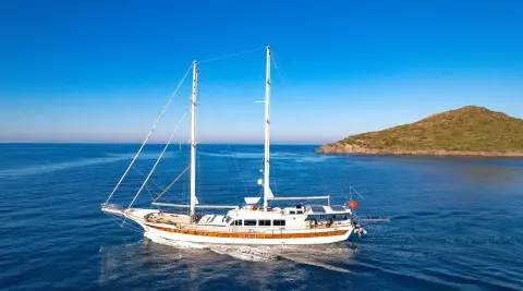 Sailing yacht with two masts cruising on blue sea, hull and deck visible