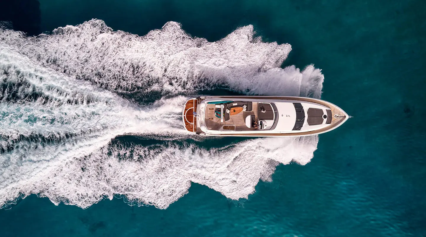 A sleek motor yacht named M Five cruises through blue turquoise water creating white wake