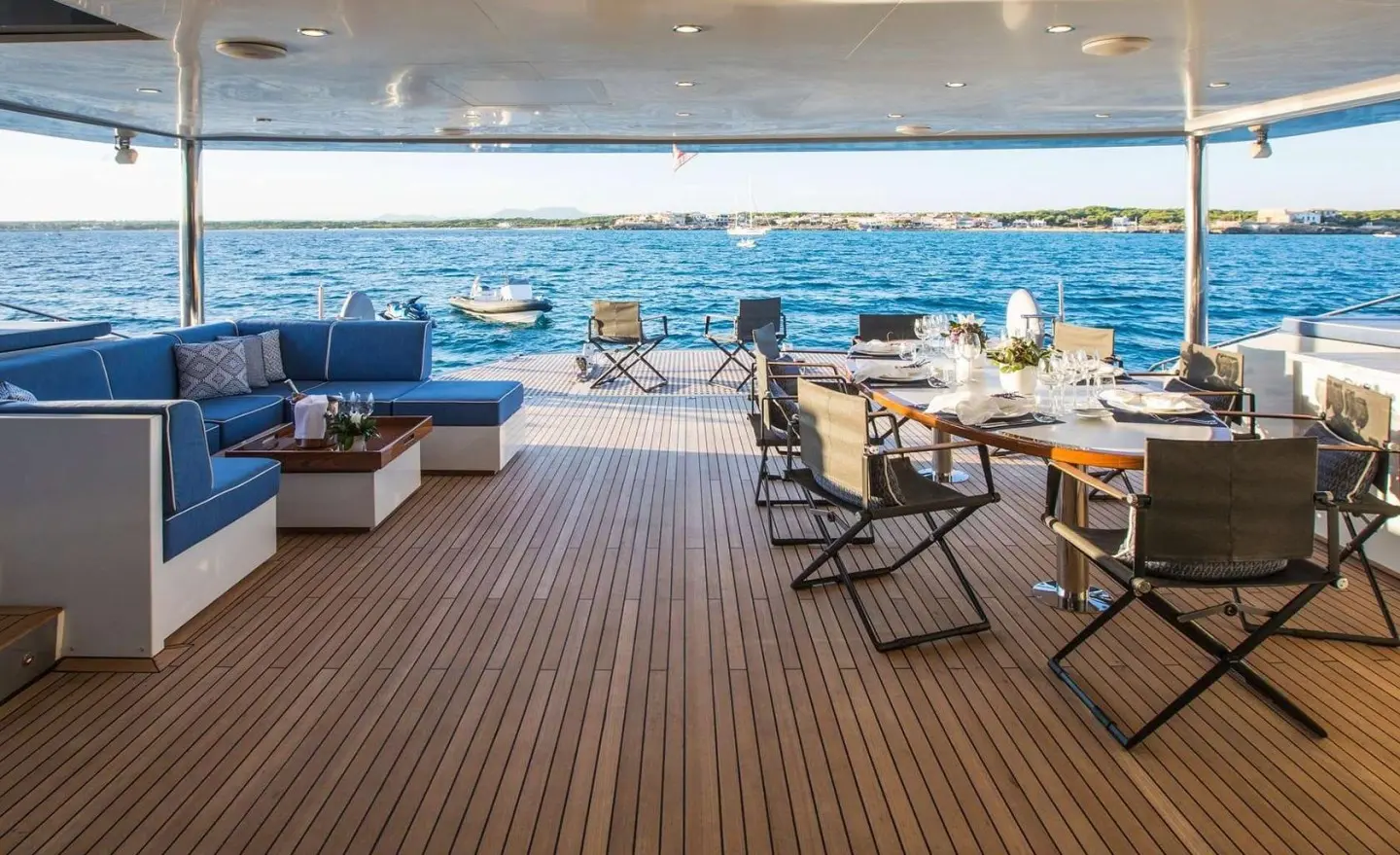 Deck seating area of Cartouche at sunset with blue ocean beyond and lounge chairs