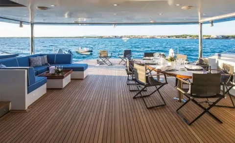 Deck seating area of Cartouche at sunset with blue ocean beyond and lounge chairs