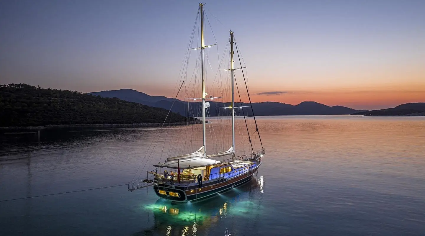 Artemis luxury gulet at sunset, anchored on calm water with colorful sky