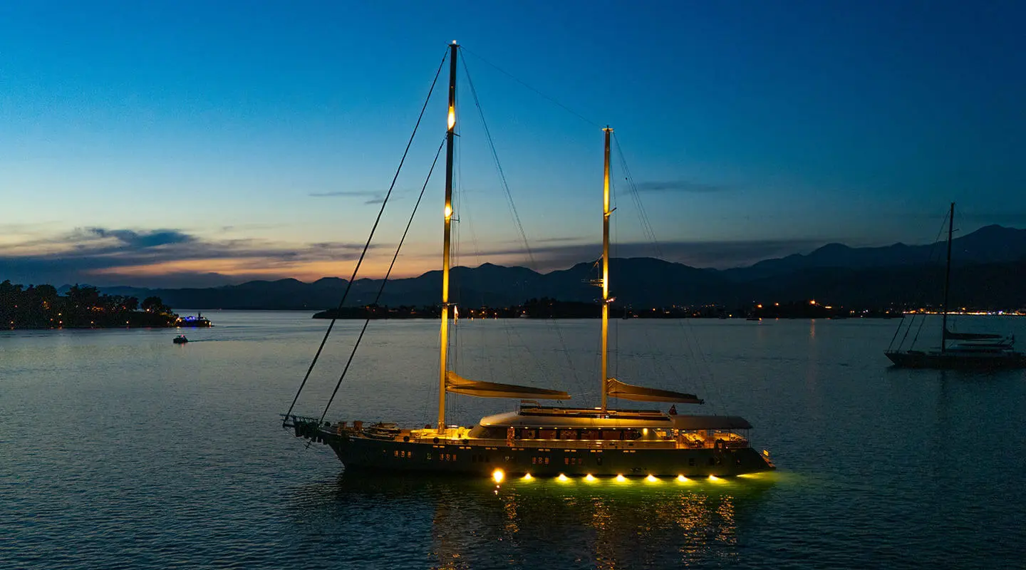 Nighttime view of King Of The Sea yacht anchored with warm lights on a calm sea