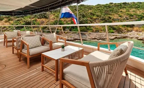 Lupus Mare yacht lounge on deck with chairs and a table at sunset