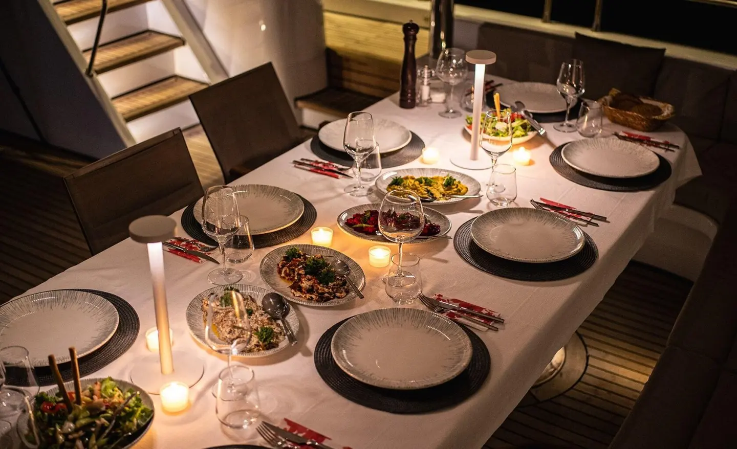Table set for dinner on Angelo III yacht with plates, glasses, and candles