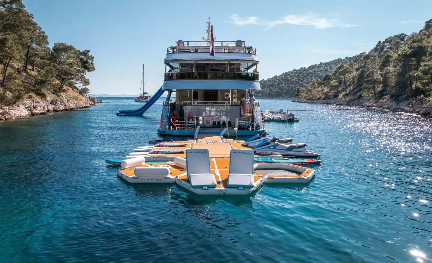 Side view of a blue motor yacht named Freedom with yellow floats attached, calm sea