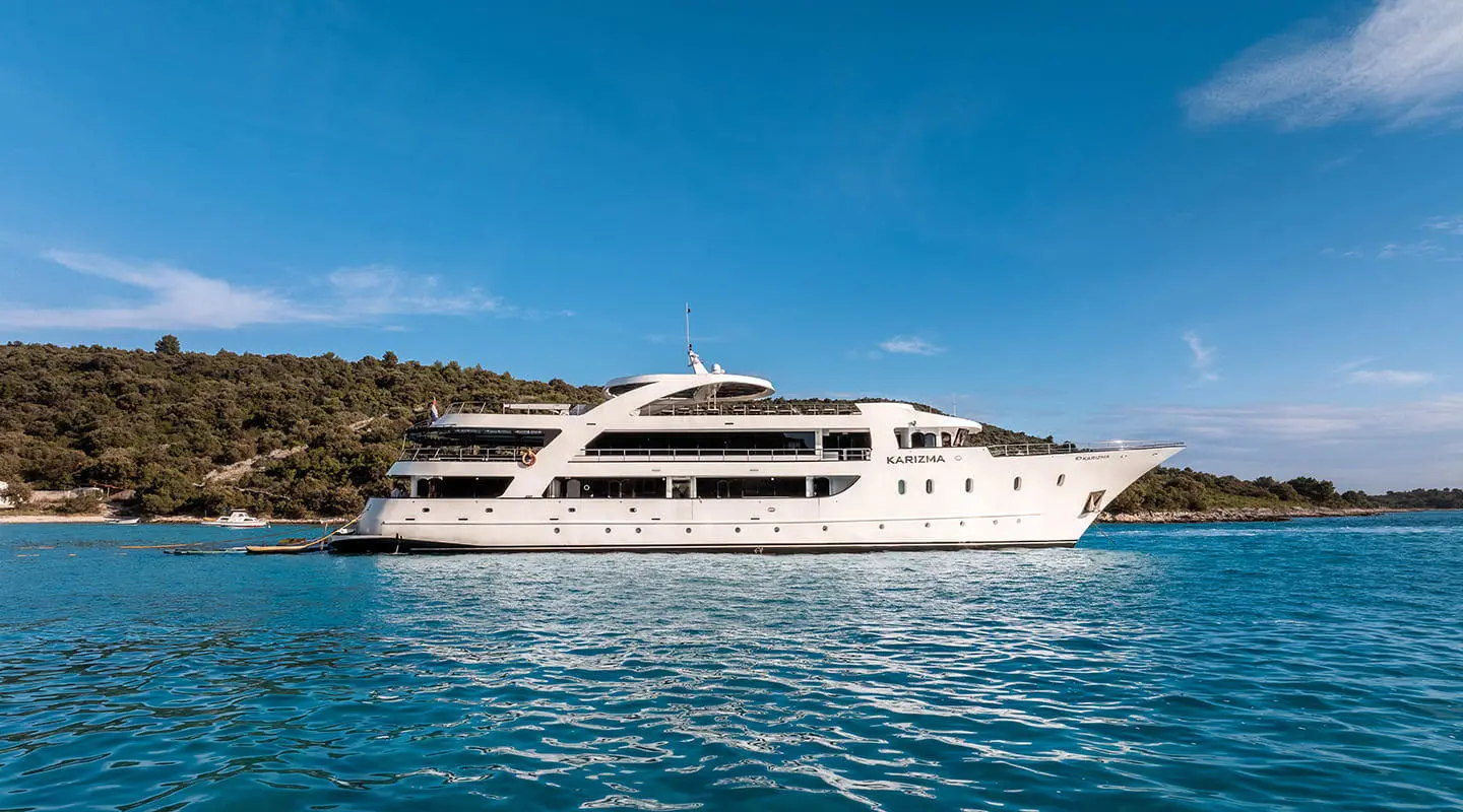 Karizma yacht anchored on calm blue sea, white multi-deck exterior