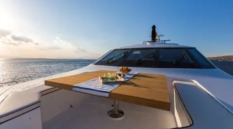Bow deck of Aquarella yacht with wooden table and drinks on board