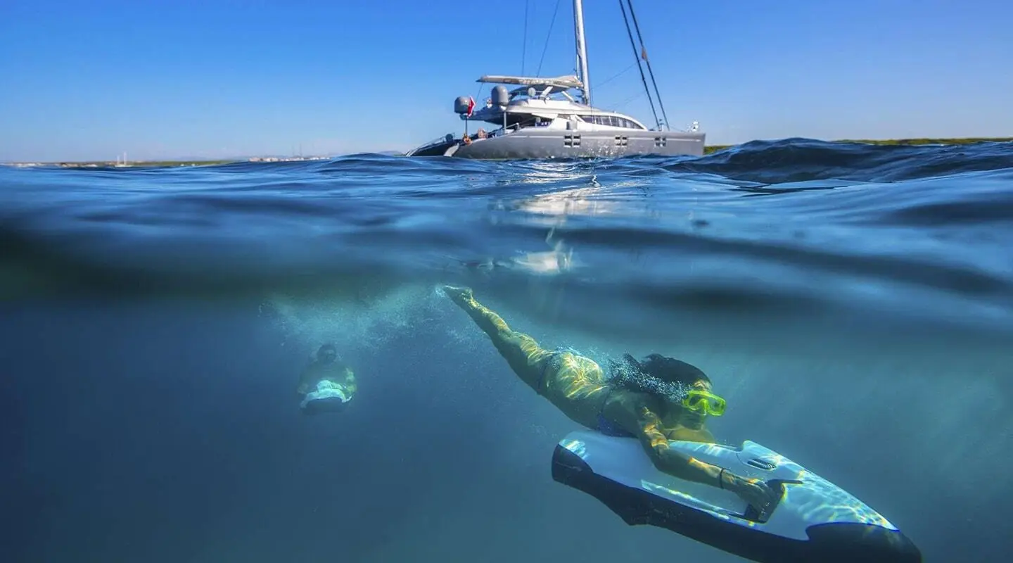 Yacht Cartouche at sea with clear blue water and a diver swimming nearby