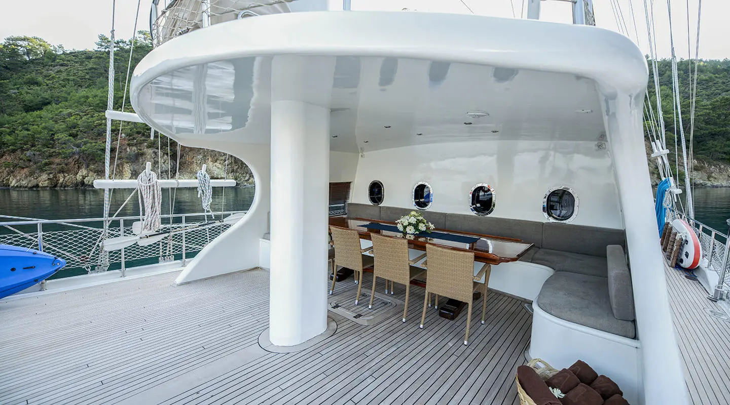 Kayhan 4 yacht on a sunset-lit deck with wicker chairs and table seating