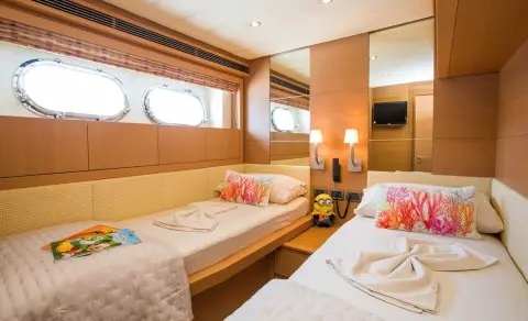 Double twin beds inside a wood-paneled cabin with porthole windows and warm lighting