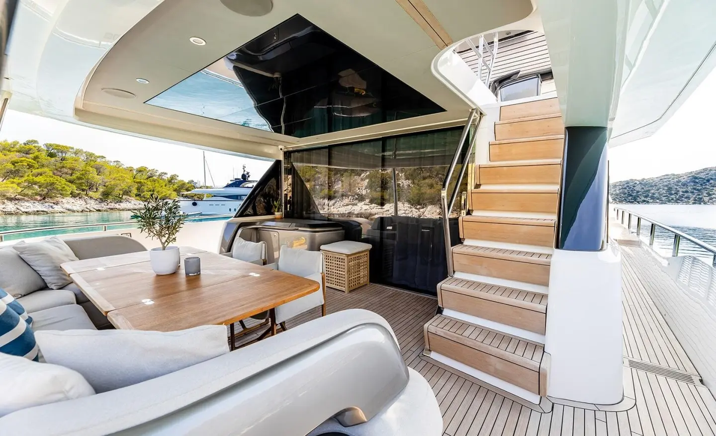 Yacht Vista aft deck with stairs, seating area, and shaded helm, sunny harbor