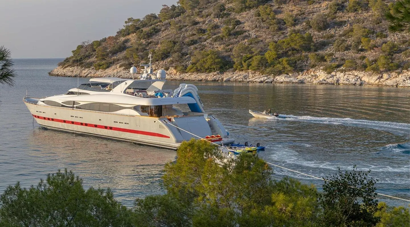 Glaros yacht anchored near rocky coastline with blue water