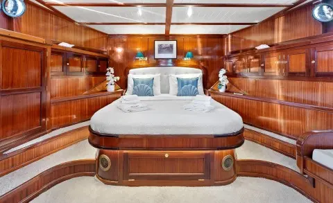 Luxurious yacht master cabin with polished wood paneling and a large bed