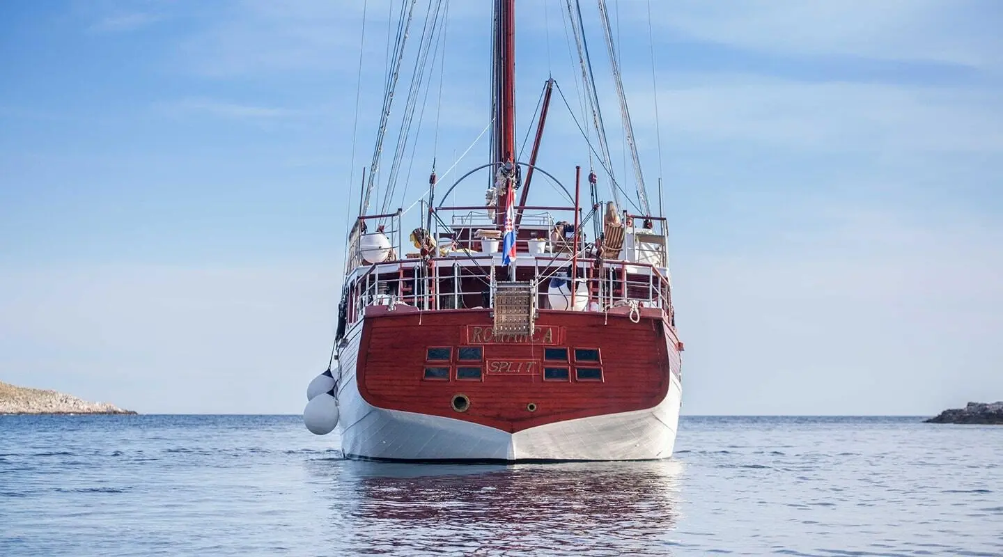 Romanca luxury gulet sailing at sunset, red hull, calm water reflections