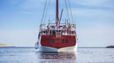 Romanca luxury gulet sailing at sunset, red hull, calm water reflections