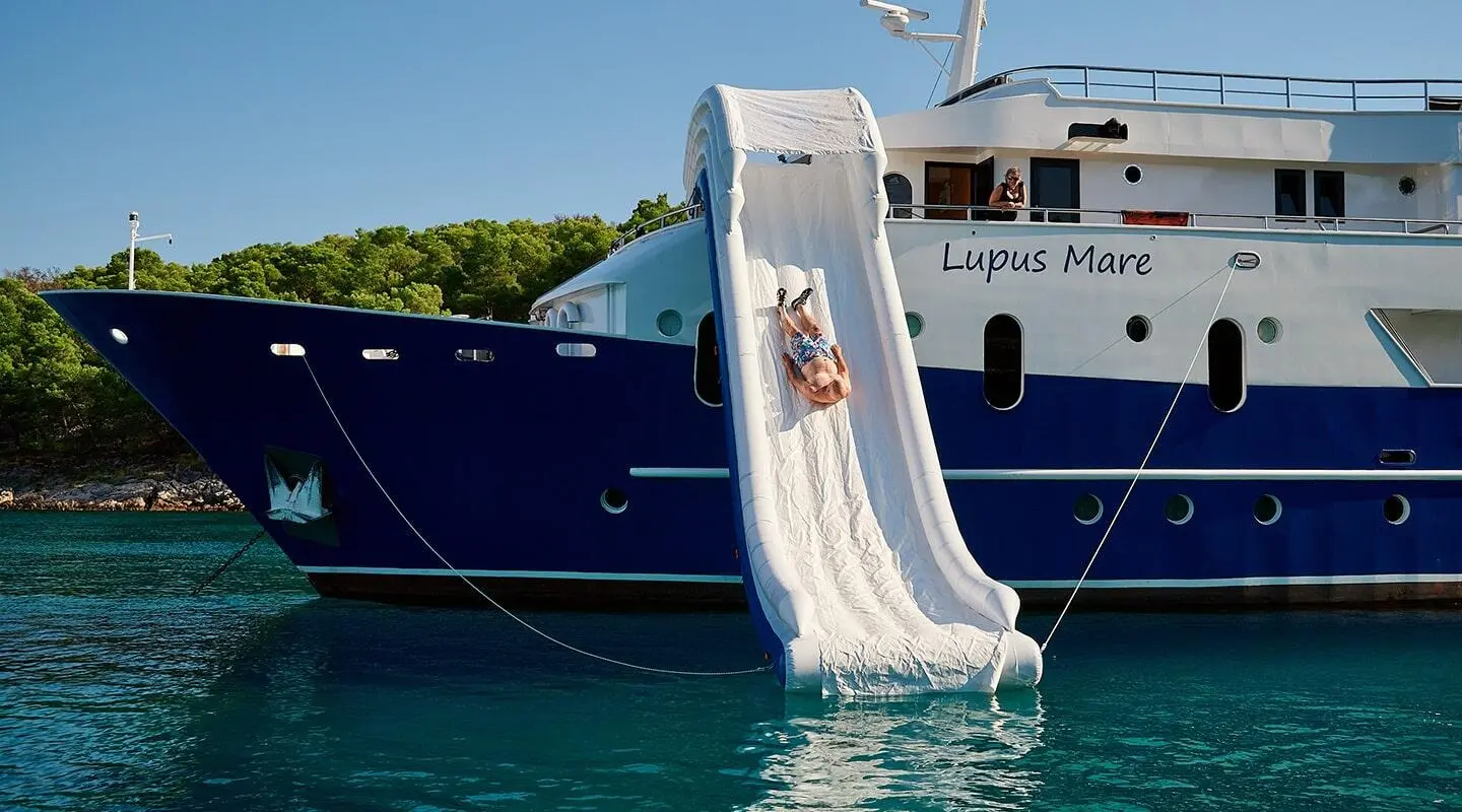 Blue luxury yacht Lupus Mare with a water slide descending into calm sea
