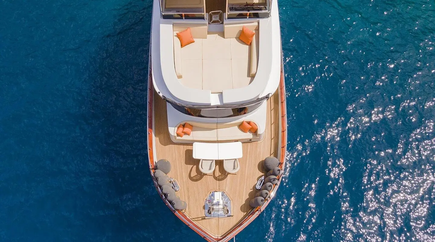 Aerial view of the Simay M yacht with wooden deck and orange cushions on blue sea