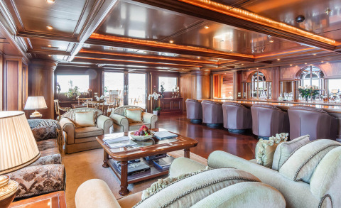 Interior of Apogee yacht with luxurious seating area, bar, and large windows