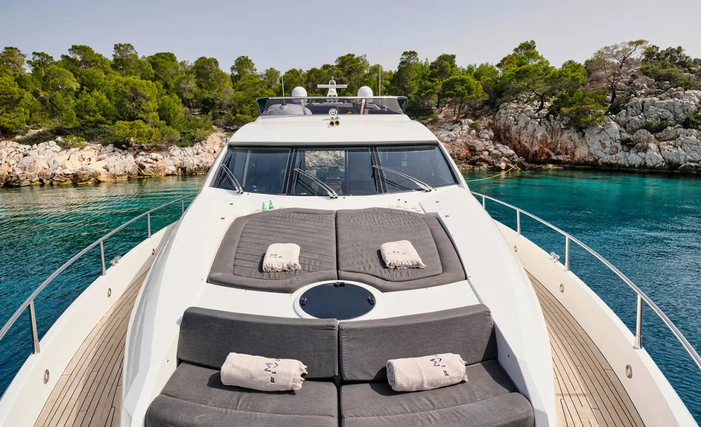 Front deck of M Five yacht with cushioned seating and sunbathing area