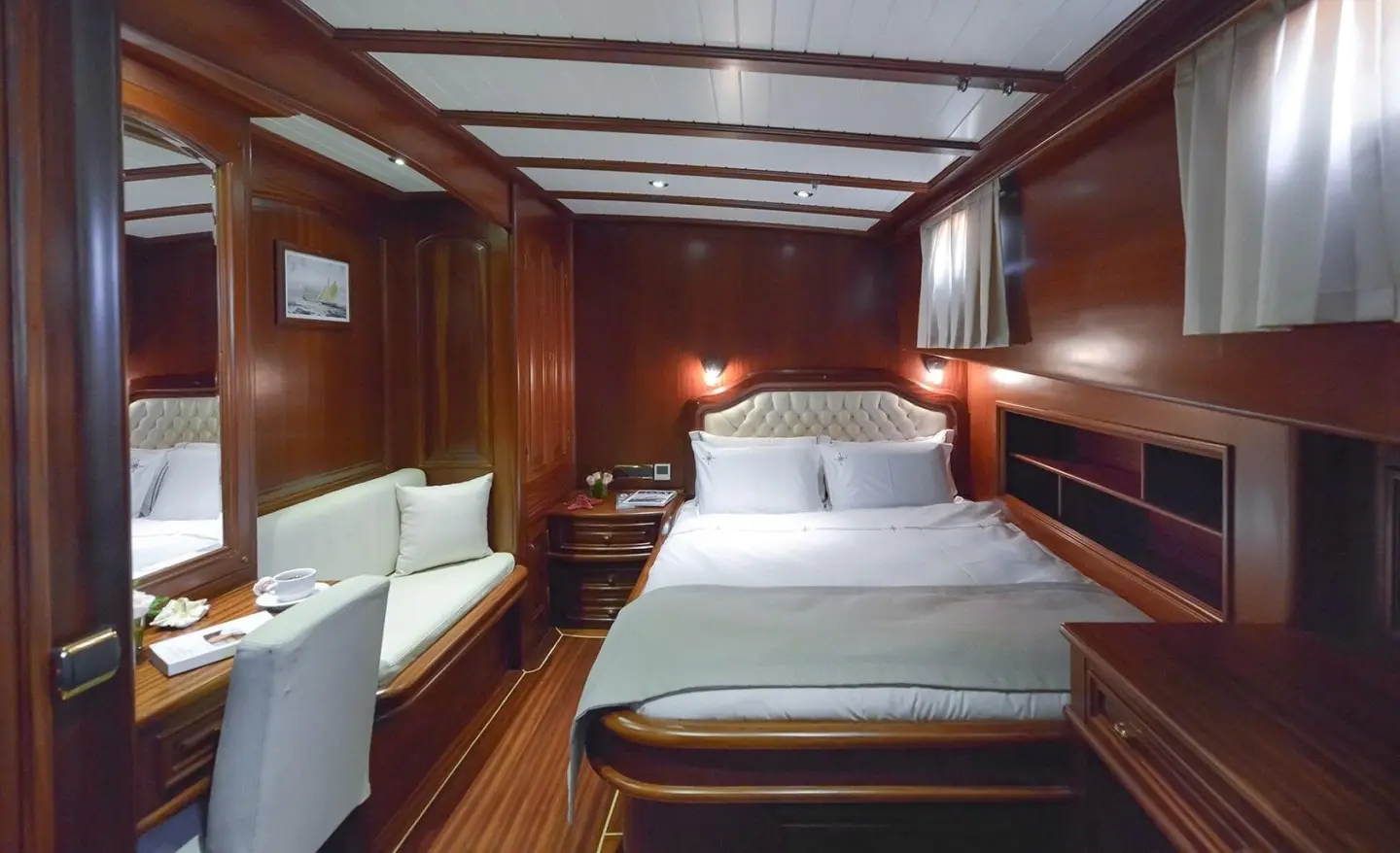 Interior of Lady Christa yacht: cabin with double bed, wooden walls, seating, warm lighting