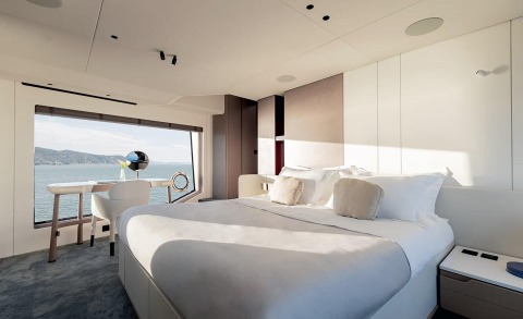 Bright yacht cabin with large window view of sea, desk and chair by window