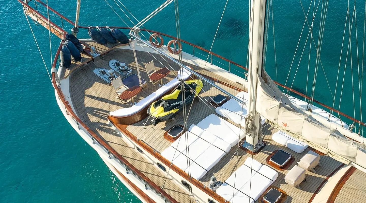 Gulet Estrella De Mar bow deck with lifebuoy, stairs, and blue water backdrop