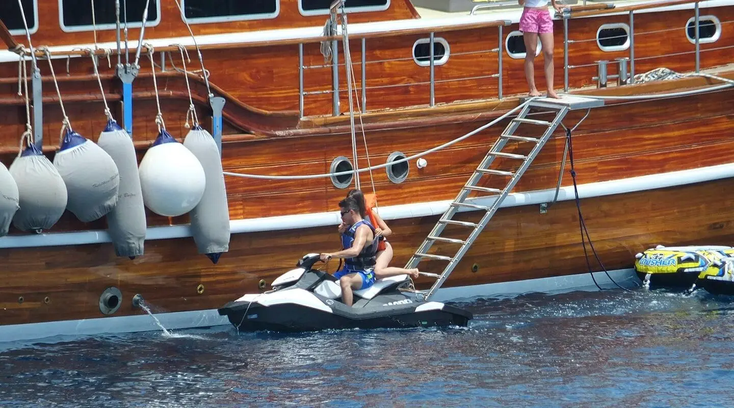 Yacht Kaptan Mehmet Bugra alongside wooden gulet, sunset hues on water