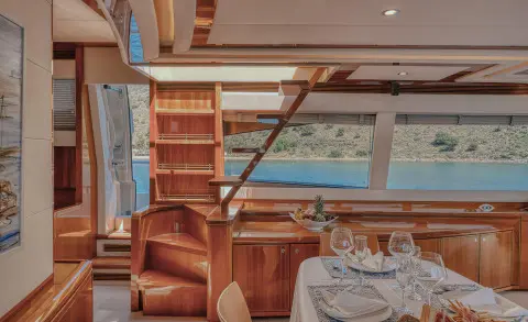 Interior of yacht Lidia saloon with table setting and stairs visible