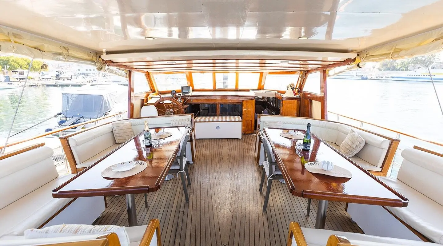 Gulet Gardelin aft deck with wooden dining tables and cushioned seating