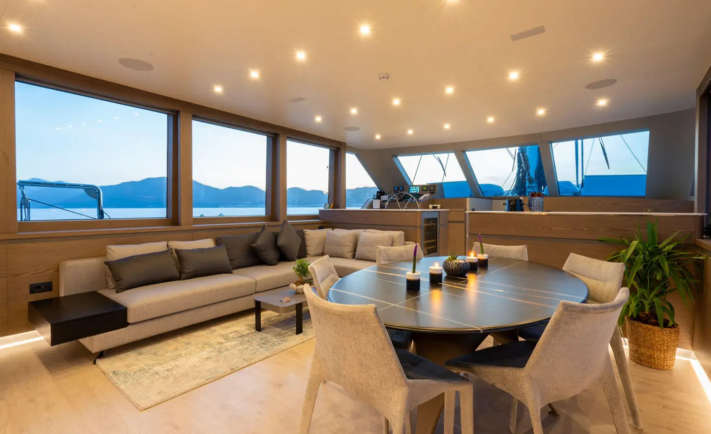 Elegant yacht interior with large windows, seating, and wooden table aboard Good Life
