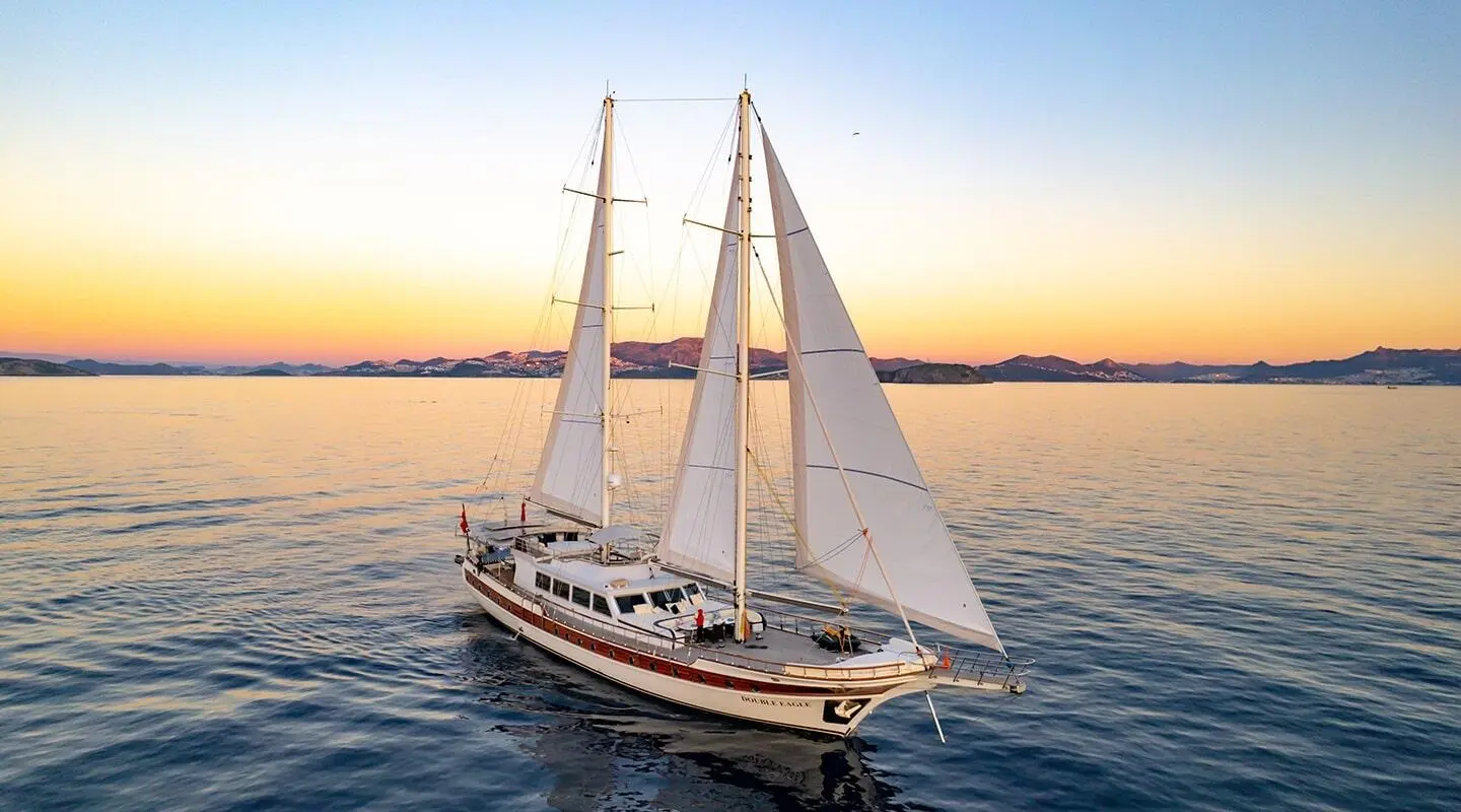 Gulet yacht Double Eagle sailing at sunset with three masts on calm water