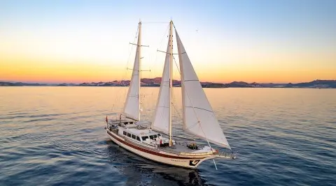Gulet yacht Double Eagle sailing at sunset with three masts on calm water