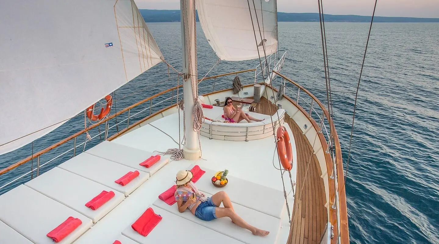 Luxury yacht deck with two people sunbathing, sea and distant shore