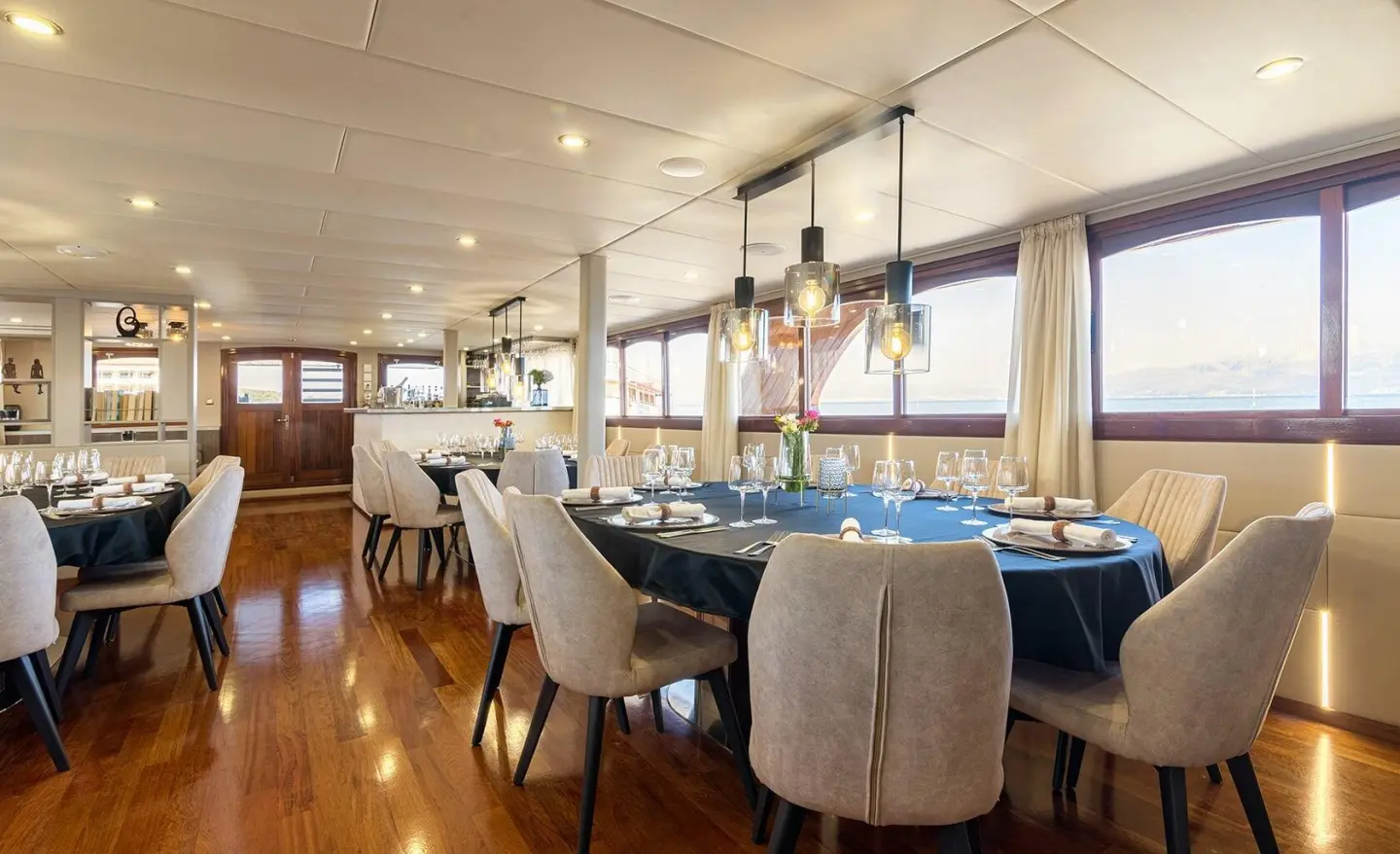 Interior of Melody yacht saloon with blue table, beige chairs, wooden floor