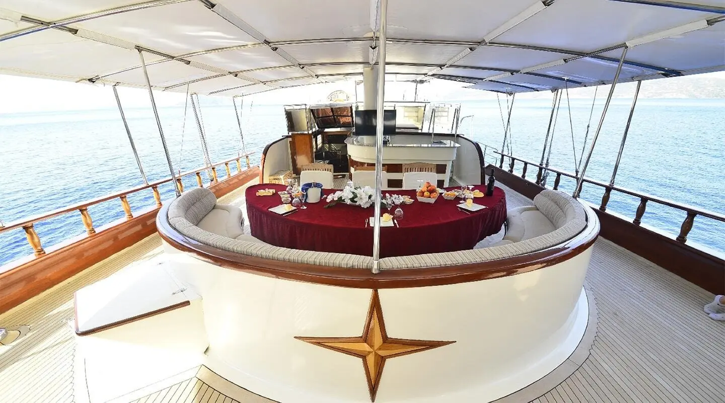 Berrak Su yacht deck seating area with red cushions and blue canopy at sunset