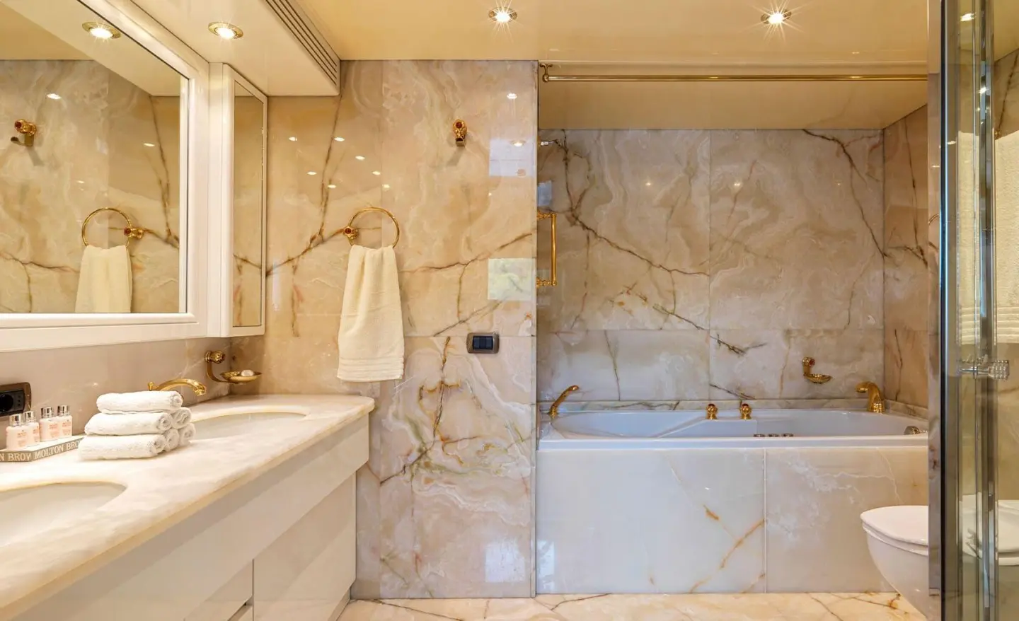 Interior of Idylle motor yacht bathroom with marble walls, shower area, and sink