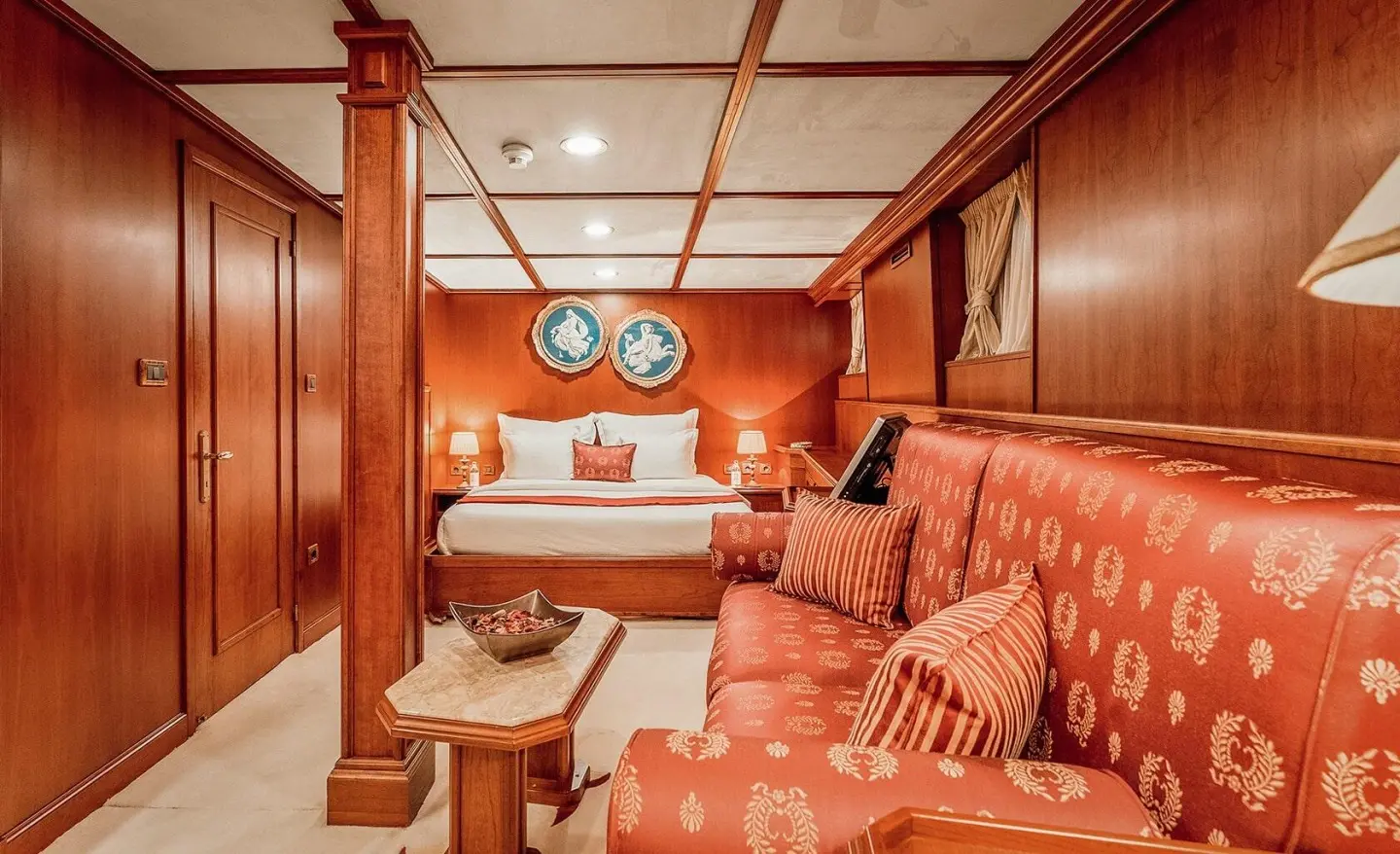 Cozy Seagull II master cabin with wooden paneling, red cushions and a sofa