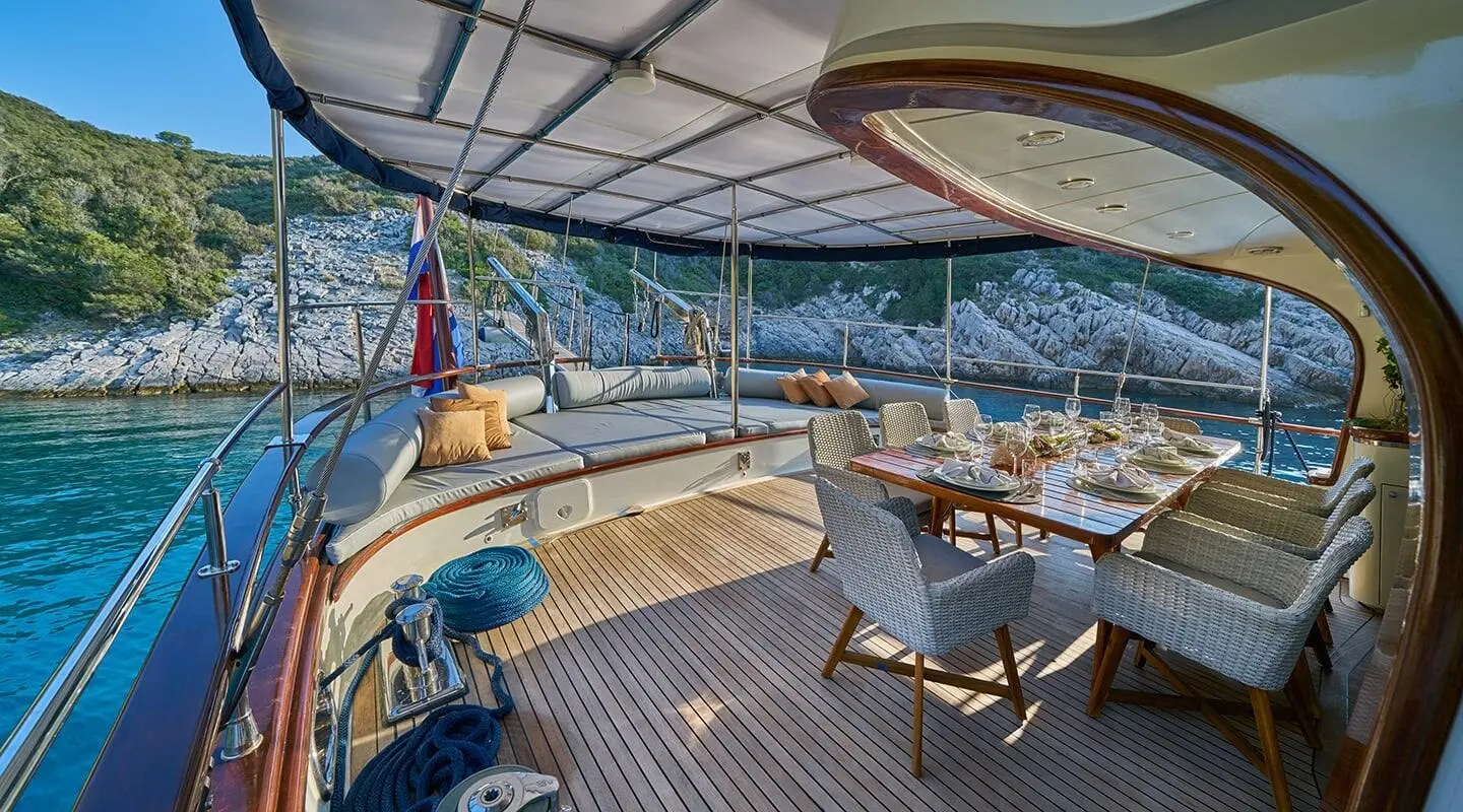 Lotus yacht charter deck at sunset with seating, ropes, and blue ocean view