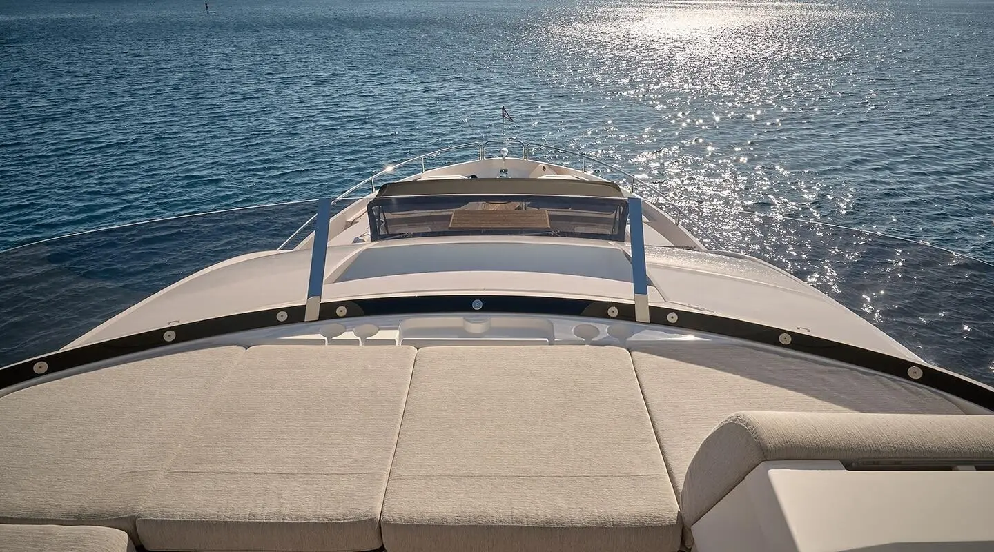 View from a yacht deck toward calm blue water with railings and sunlit horizon