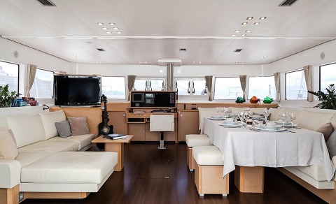 Aizu yacht interior with a salon area and dining table, white sofas and modern equipment