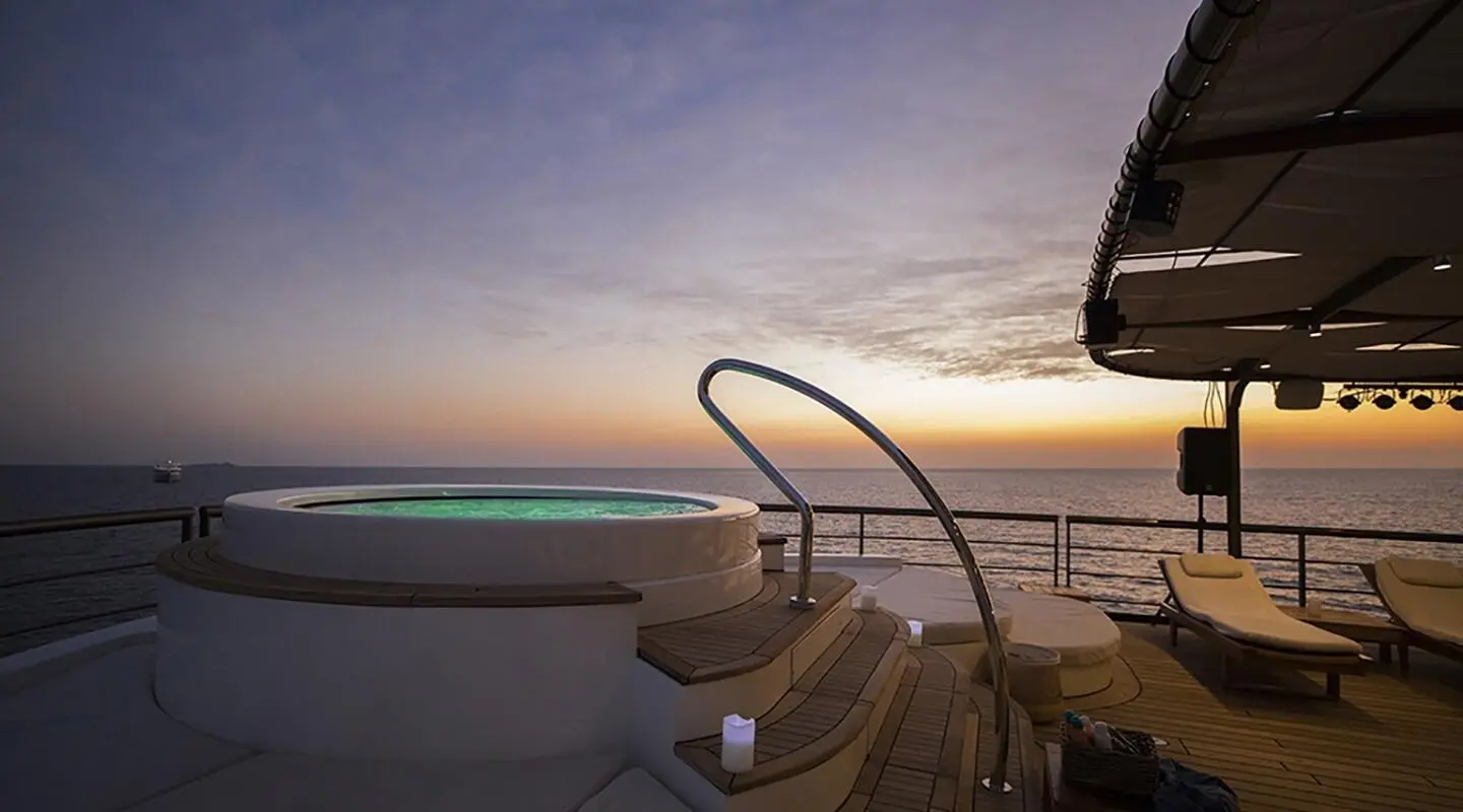 Sunset over calm sea viewed from yacht deck with railings and steps