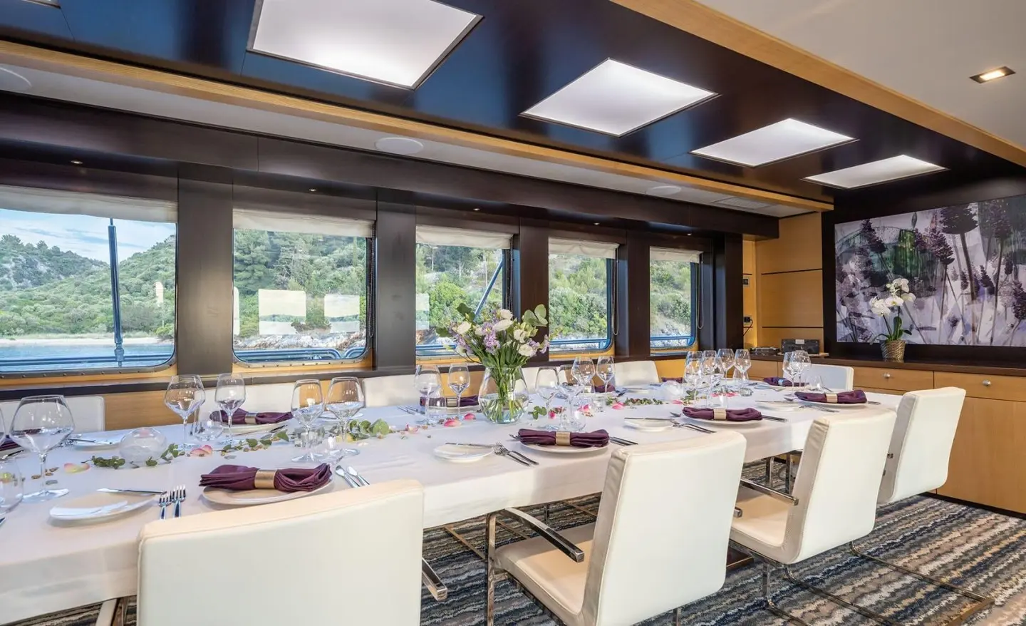 Navilux yacht salon interior with long dining table and white chairs