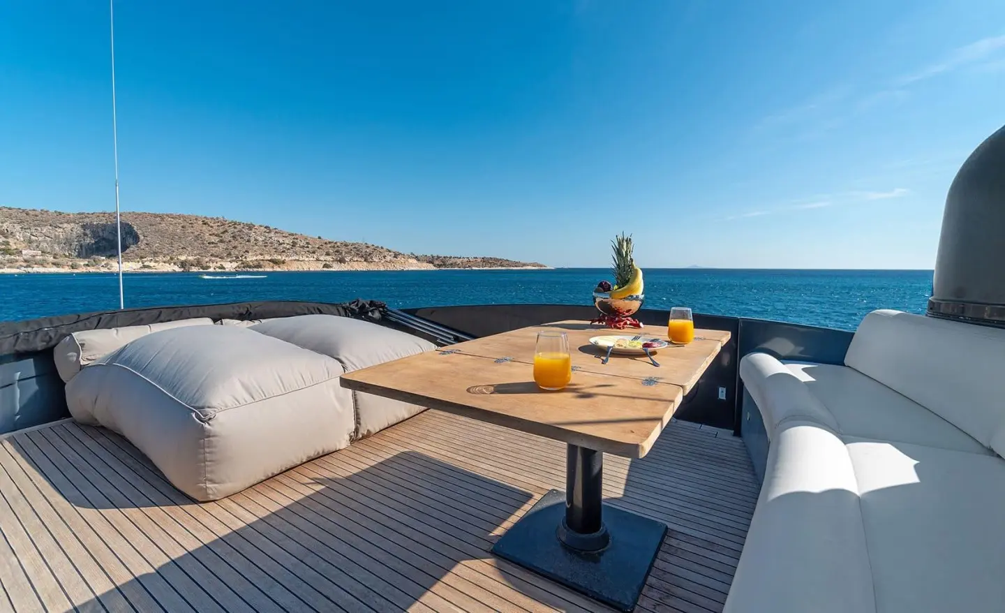 A luxury yacht bow deck with seating, table, and ocean view
