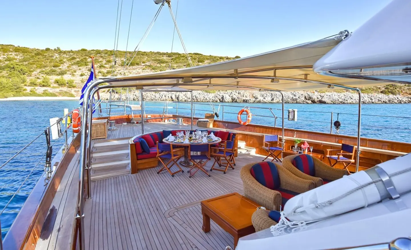 Tamarita yacht deck with seating, table, sun loungers, and blue sea backdrop