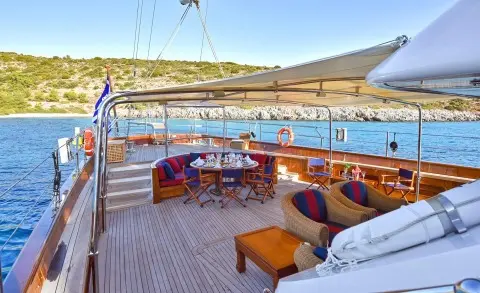 Tamarita yacht deck with seating, table, sun loungers, and blue sea backdrop