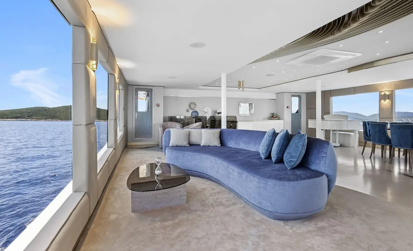 Interior of Bella yacht with a curved blue sofa and glass coffee table