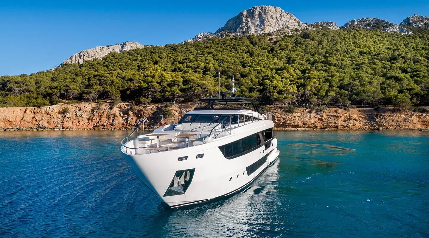 Luxurious white Spica motor yacht anchored near rocky shoreline with blue water