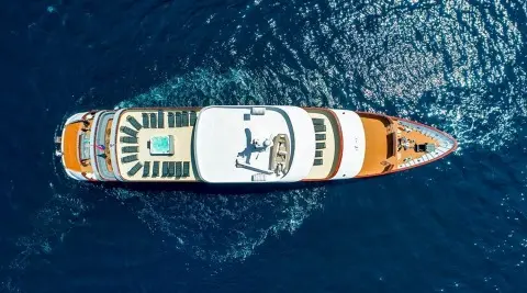 Aerial view of a luxury yacht named Yolo cruising blue ocean at dusk
